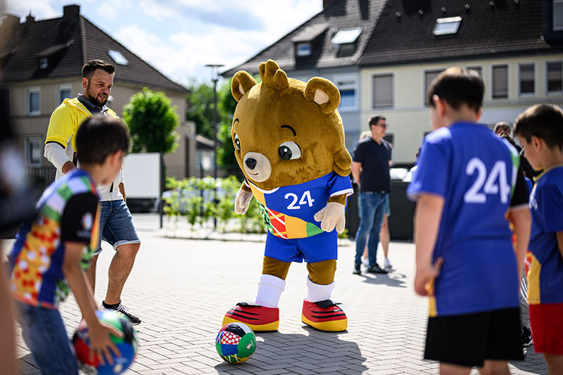 EK mascotte voetbalt met kinderen op straat