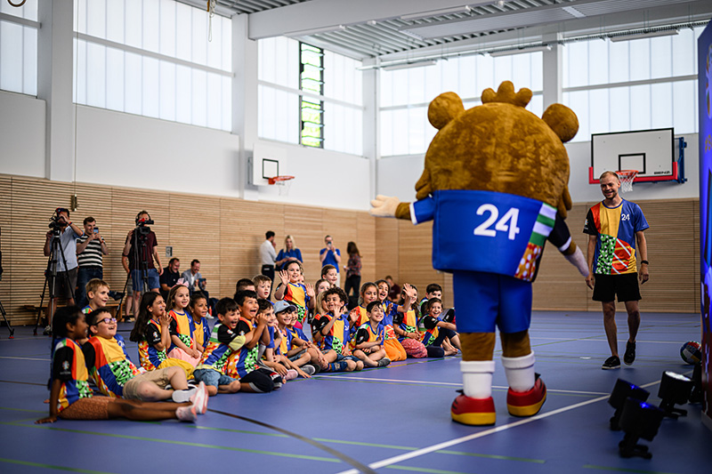 De mascotte van het EK 2024 geeft voorlichting in een gymlokaal